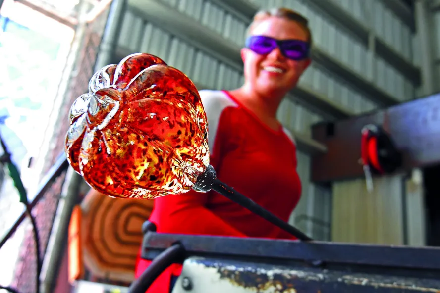 Eine Frau hält ein orangefarbenes Kunstwerk aus Glas in einem angesagten Laden