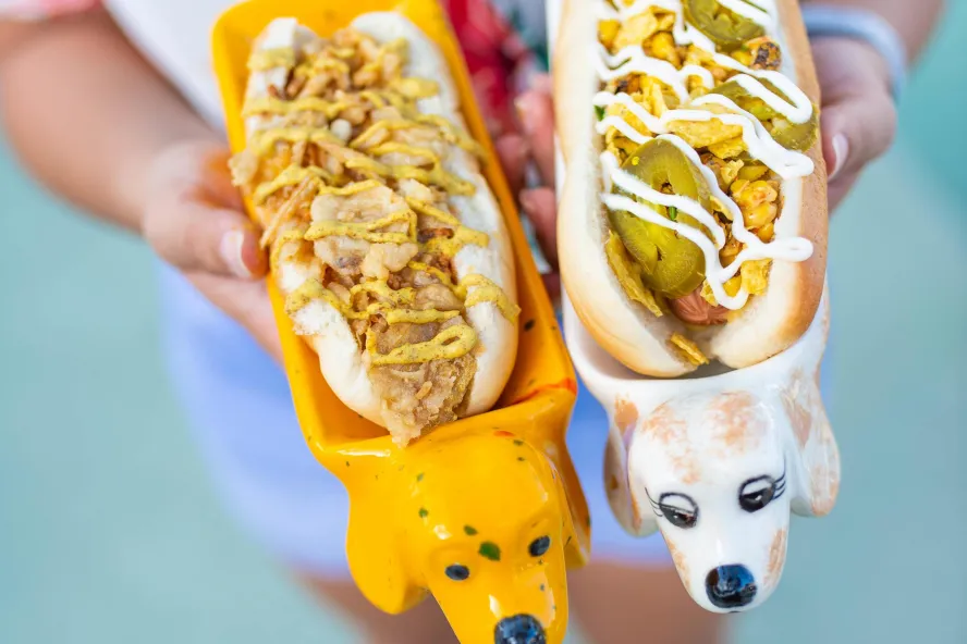 Two vegan hot dogs in cute dachshund-shaped dishes