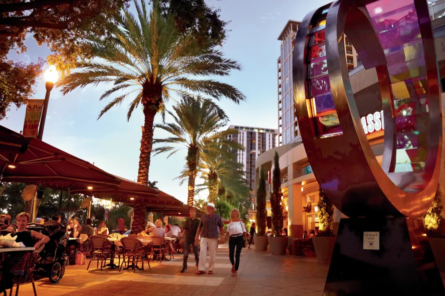 A family walks past diners at outdoor tables at Cassis in downtown St. Pete at dusk, 