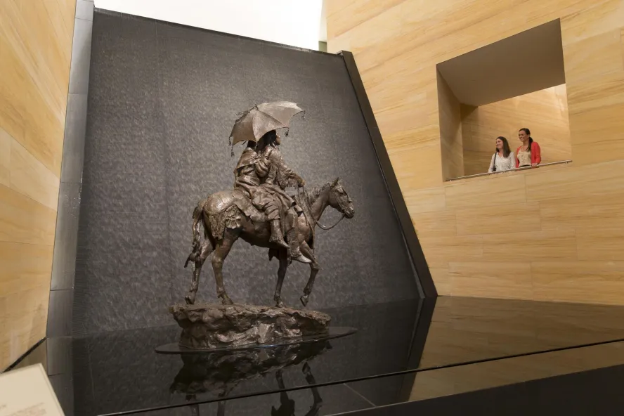 Two people peer at the waterfall and sculpture in the James Museum lobby.