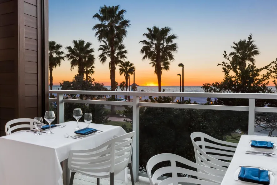 white chairs and a table with a white table cloth at Ocean Hai restaurant overlook sunset at the beach