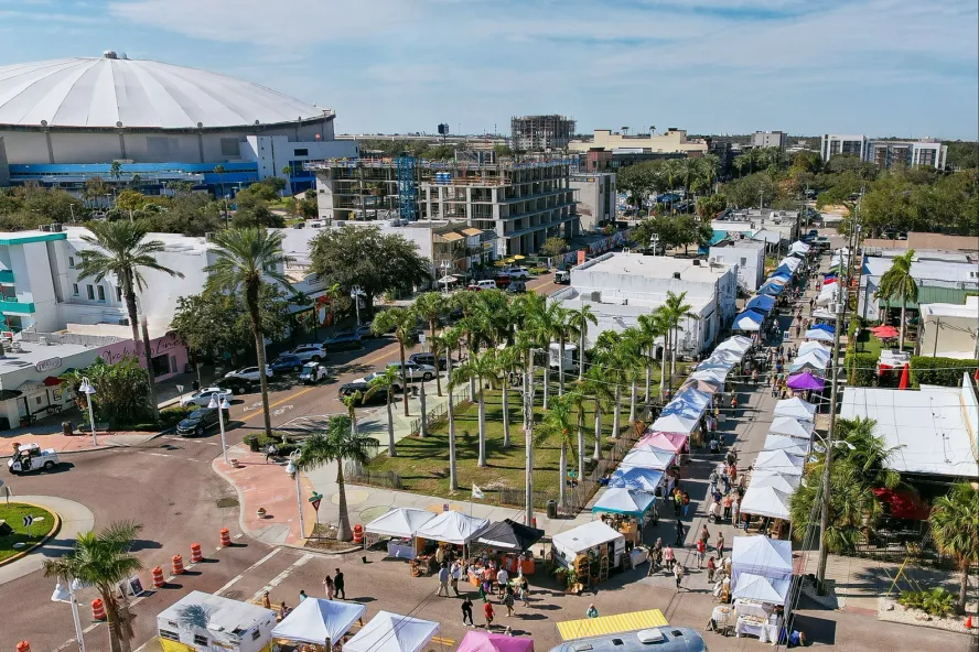 Aerial photo of the Mezzo Market in downtown St. Pete featuring a blue sky, Tropicana Field and dozens of market tents lined up.