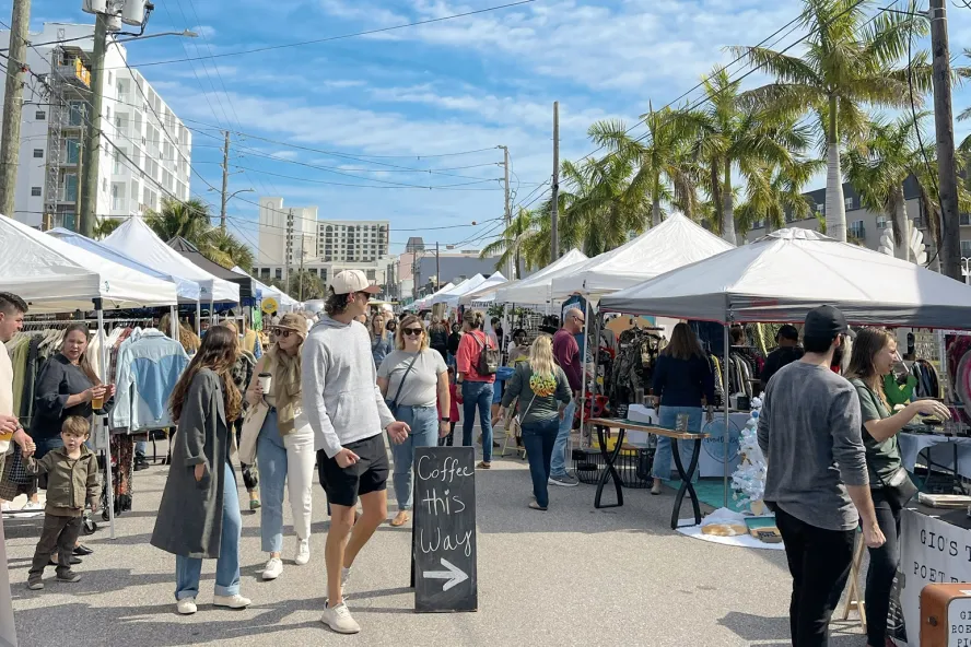 A crowd of people walking outside at the Mezzo Market in downtown St. Pete, FL.
