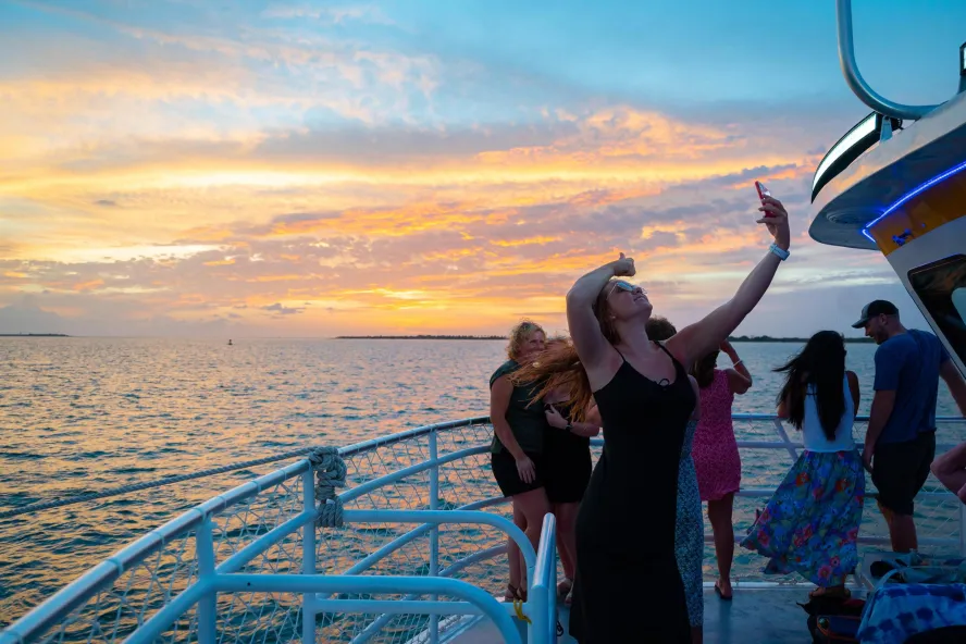 Woman taking a selfie aboard a sightseeing boat at sunset