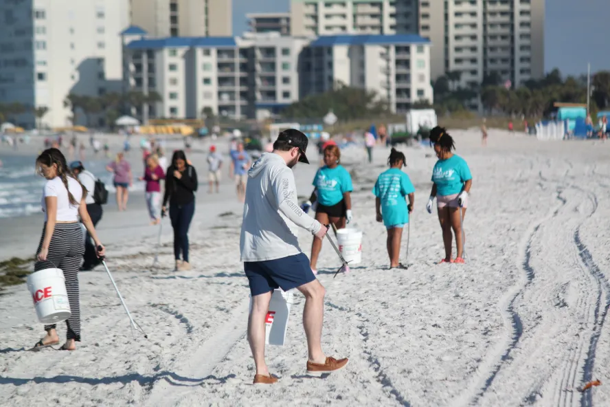 People clean up trash on the beach