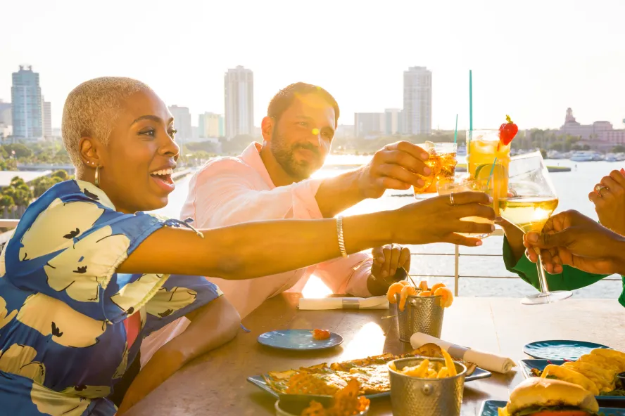 a group of friends toasting with drinks at Pier Teaki at the St. Pete Pier