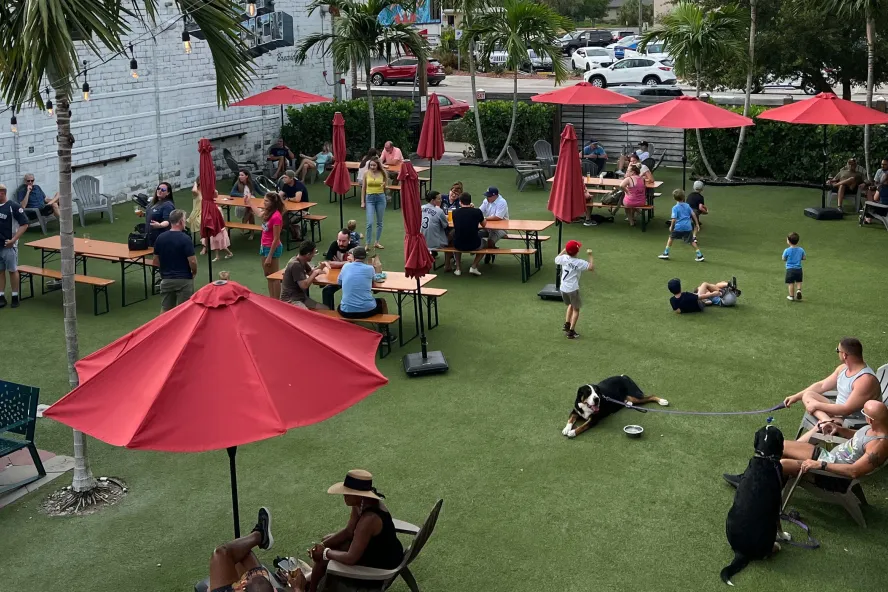 Outdoor patio with people, dogs and red umbrellas