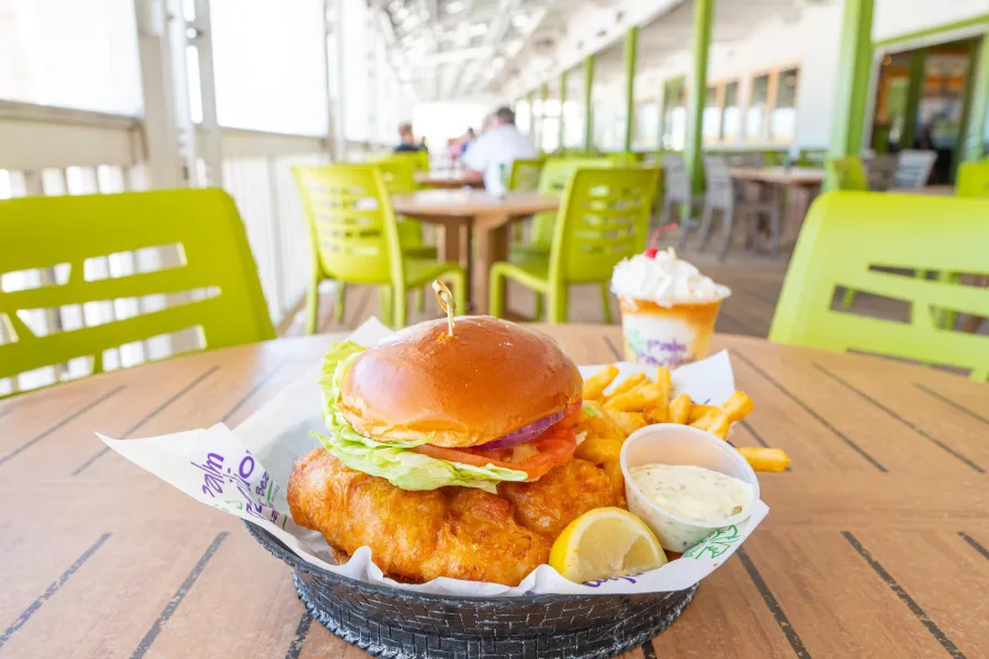 A fried grouper sandwich on a brioche bun with tartar sauce and a lemon at Crabby's Beachside Pavilion.