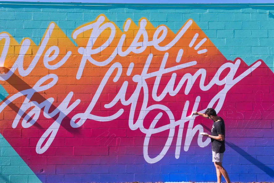 artist leo gomez paints a mural entitles we rise by lifting others