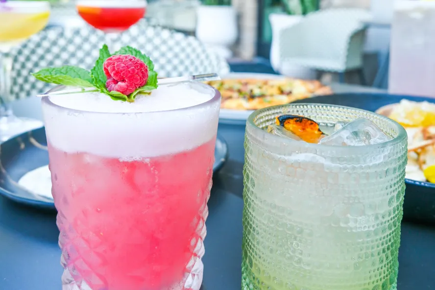a frothy pink cocktail with a raspberry and a mint leaf next to another cocktail at the Sonder Social Club in Dunedin