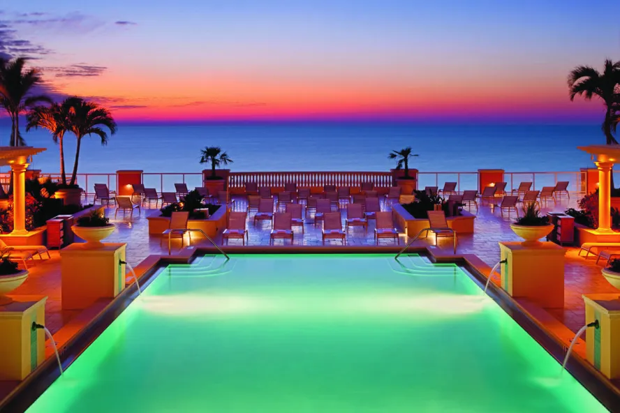 a bright pink orange sunset over a lighted pool and palm trees at the Hyatt Regency Clearwater Beach