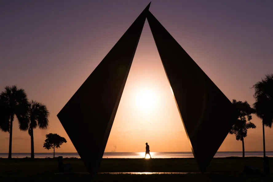 a pink and gold sunrise over palm trees and the geometric Truth scuplture in Vinoy Park St. Pete