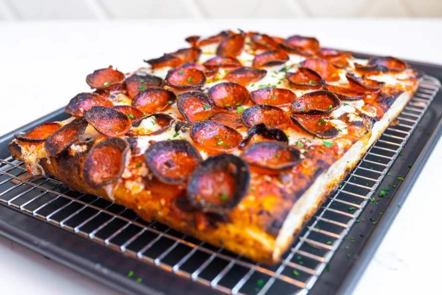 A square, thick-crust pizza with charred pepperoni