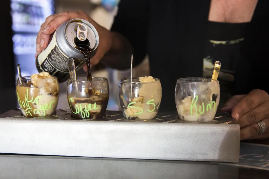 a woman pours a dark beer over a flight of gelato in 4 flavors