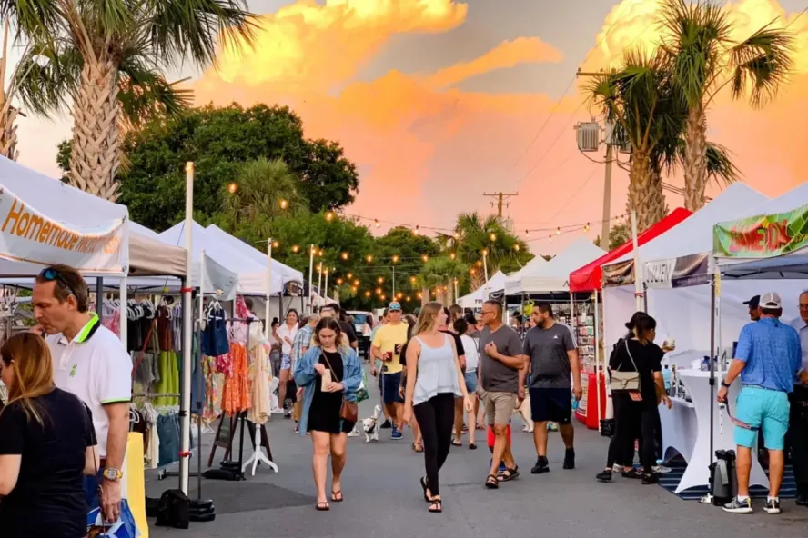 Outside sunday market in St. Pete featuring multiple white vendor tents and groups of people shopping and walking around.