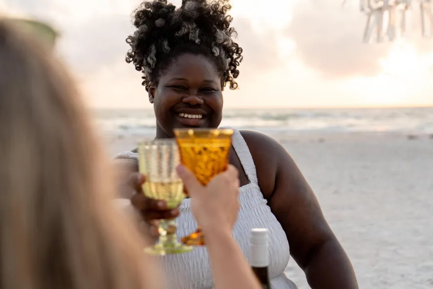 two women make a toast a a beach picnic