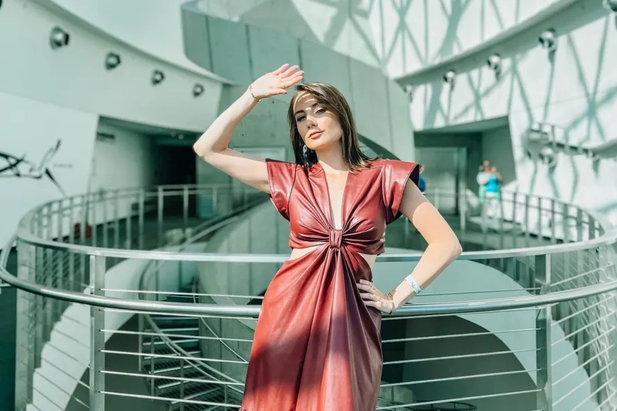 a glamorous woman in a rust-colored dress poses in the atrium at the dali museum