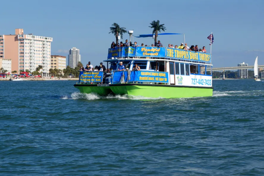A tropical-themed tour boat cruises through the water during the day.