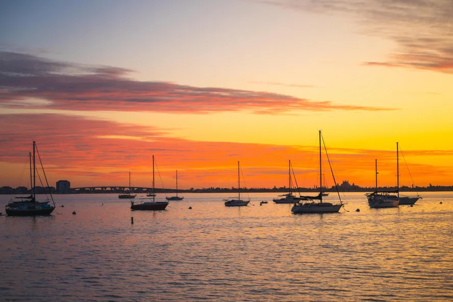 a brilliant orange and yellow sunset with sailboats anchored in the bay in Gulfport