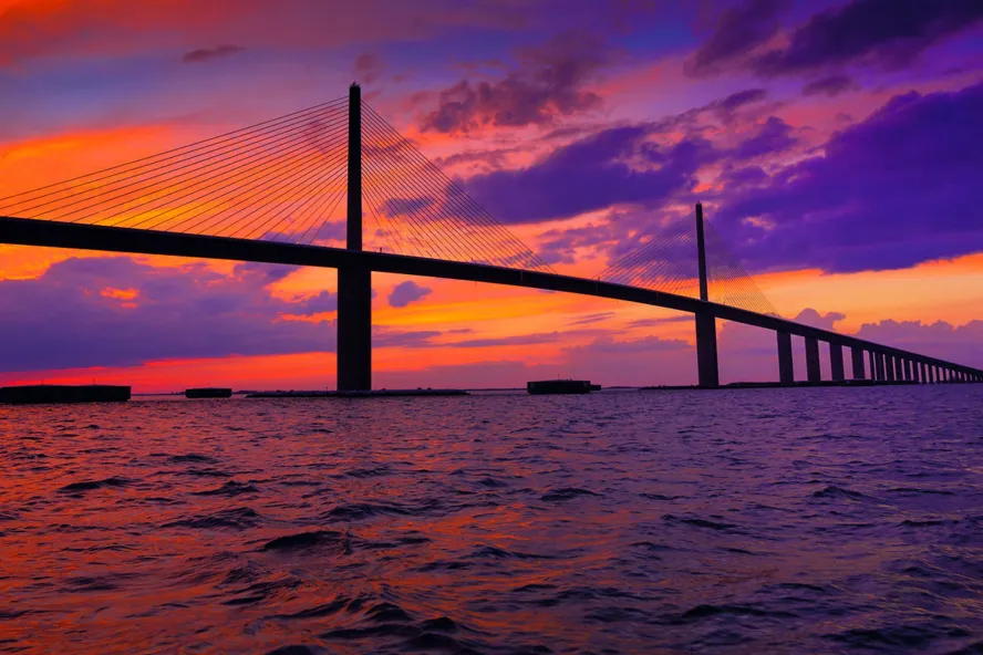 a gorgeous sunset in pinks and oranges behind the Sunshine Skyway Bridge in Tampa Bay