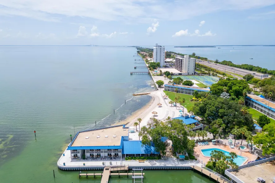 an aerial view of a waterfront hotel with a pool and pickleball courts at SkyBeach Resort
