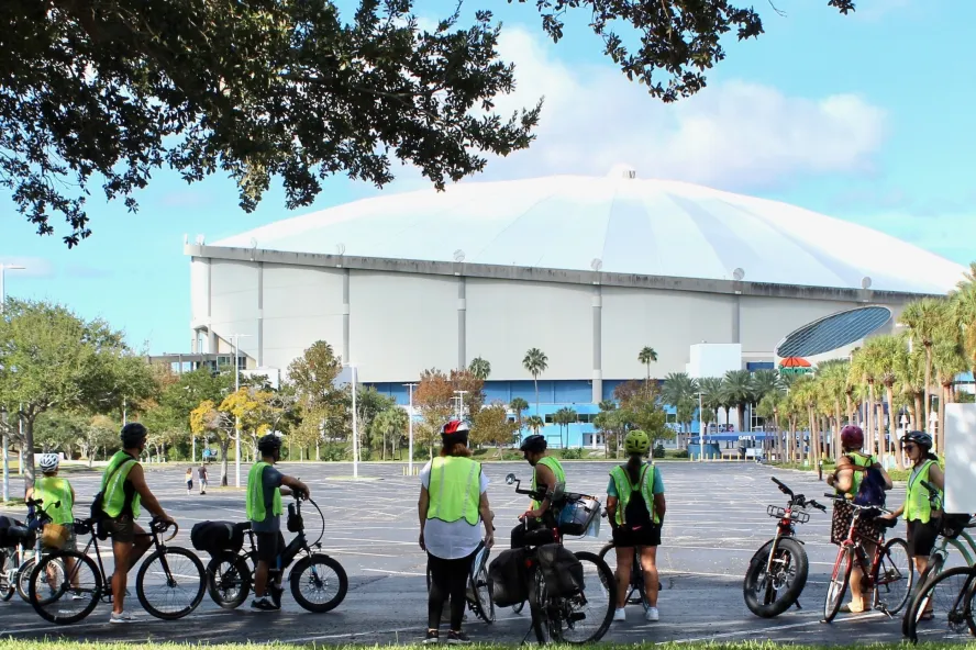a group of bike riders in yellow safety vests stops to listen to a tour guide