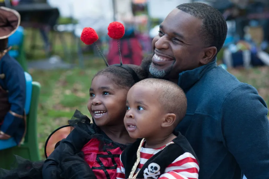 Father and his two kids sitting on his lap in a park.