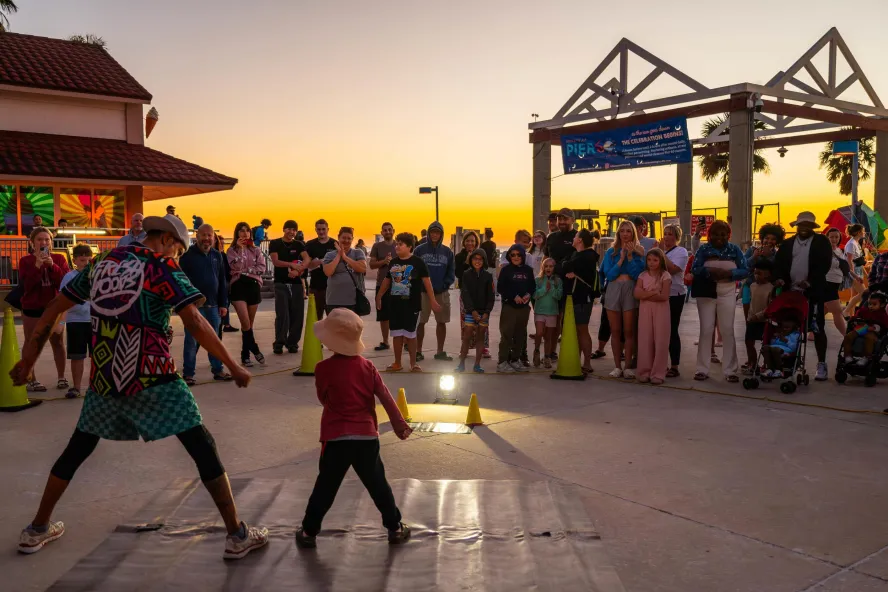 a performer engages with a small child at the sunsets at Pier 60 nightly celebration