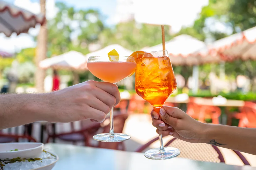 two diners toasting with their drinks at Juno & the Peacock in St. Pete