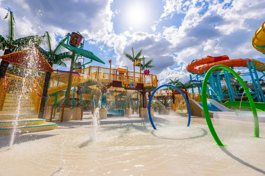 the colorful outdoor water play area with water slides, water shooting up out of the ground and stairs leading to more levels of interactive water fun. 