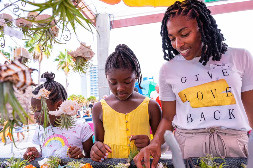 a woman and her two daughters looking at plants for sale at the Sunsets at Pier 60 celebration