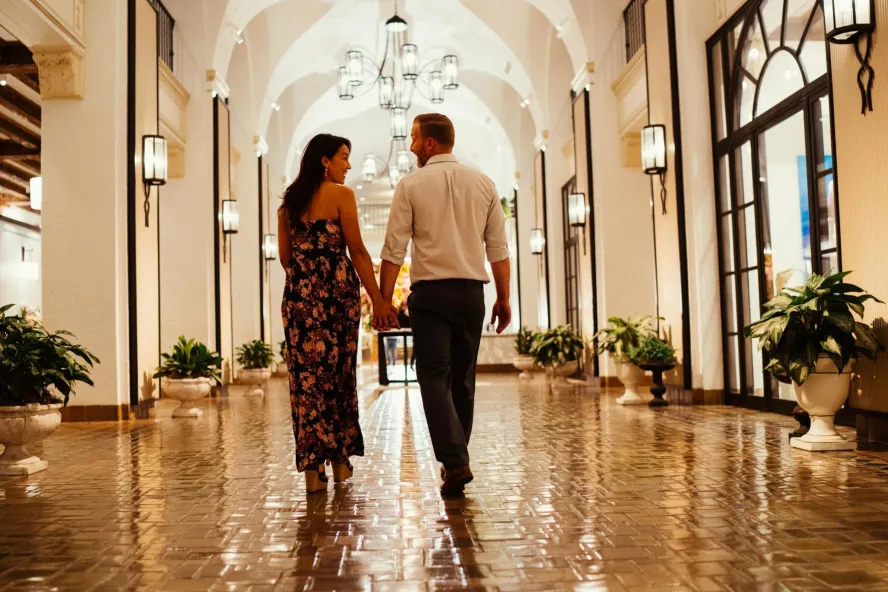 a woman and a man walk down a shiny tiled hallway with arched ceilings at the Vinoy Resort & Golf Club