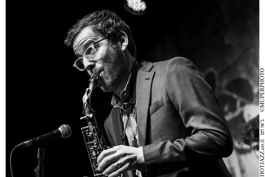 Black and white photo of a man playing the saxophone on stage.
