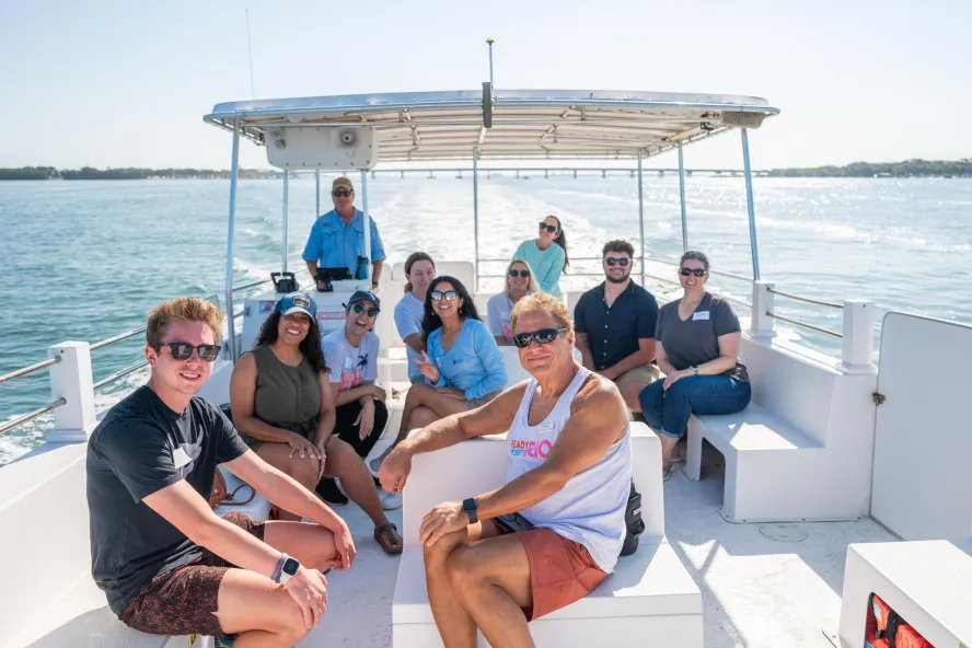 a group of people on a boat with mangrove islands in the background