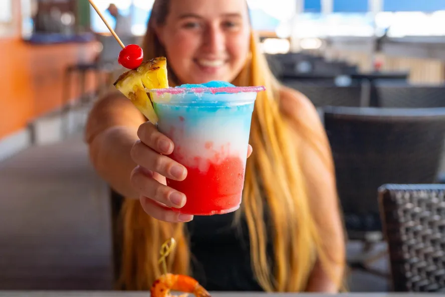 A young woman holds up a festive drink at Sloppy Joe's in Treasure Island