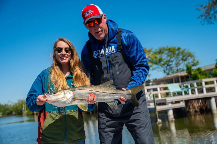 A woman and a captain hold up a snook for a picture