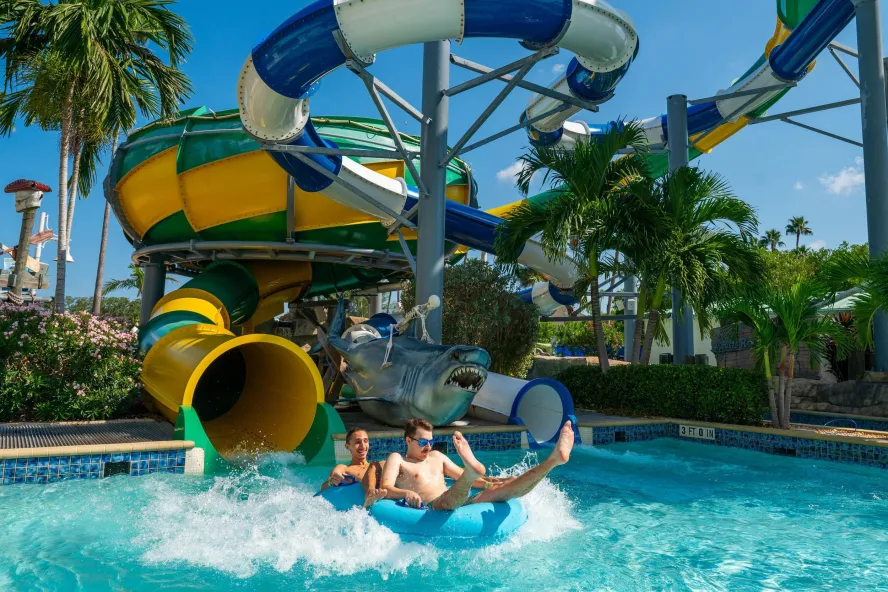 two people in inner tubes splash down into a pool from a twisty water slide at Splash Harbour Water Park