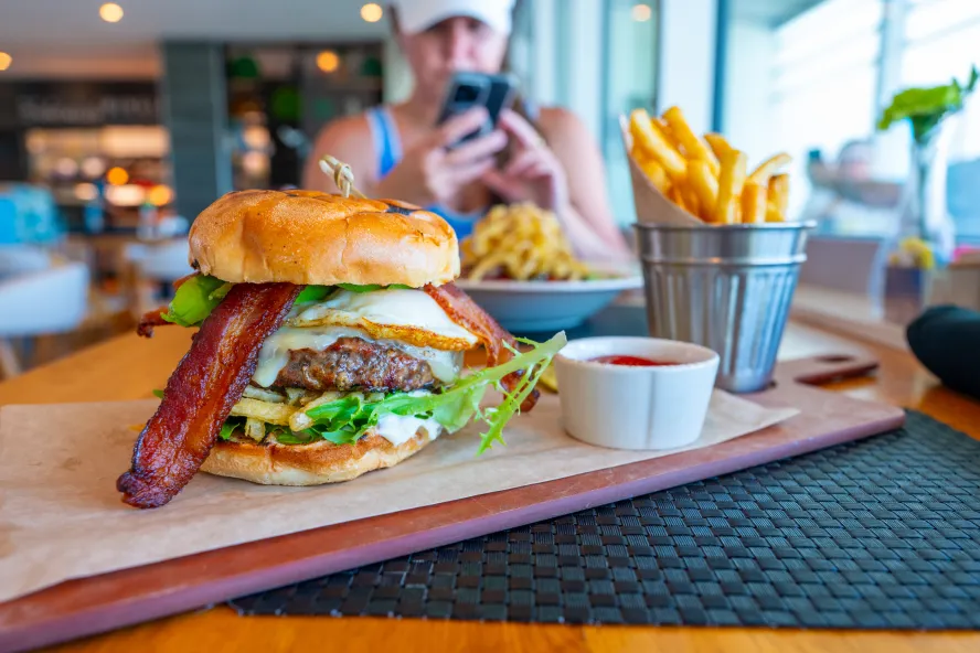 a big juicy burger with cheese and bacon on a wooden board with a metal bucket full of fries at BRGR Kitchen & Bar in Treasure Island