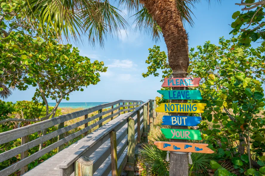 boardwalk bridge to the beach with a sign that says "please leave nothing but your footprints"
