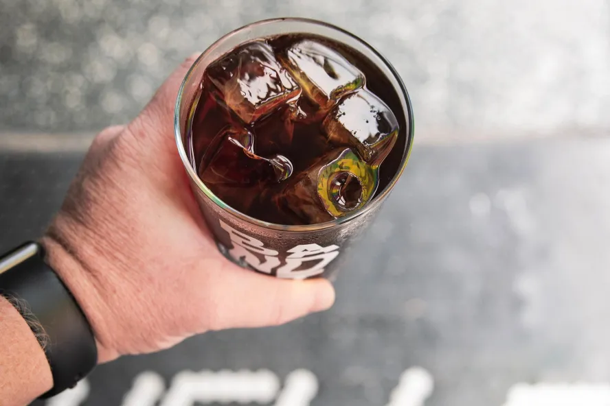 a person's hand holding a glass of iced black coffee at Bandit Coffee Co.
