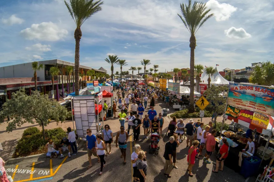 many people walking near food trucks and vendors at the John's Pass Seafood Festival in Madeira Beach