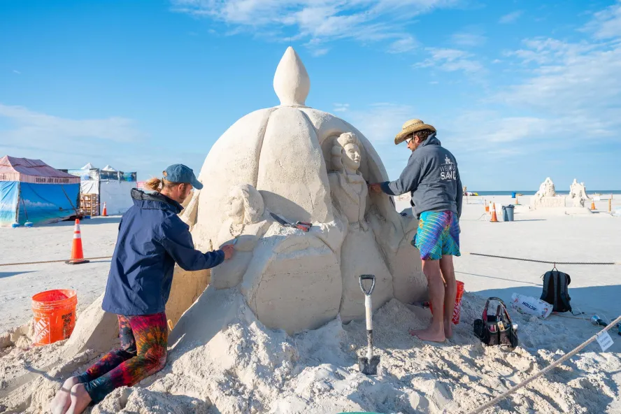 two people working on a sand sculpture at Sanding Ovations Master's Cup