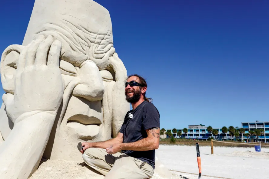 a sculpture working on a sand sculpture of a giant head at Sanding Ovations