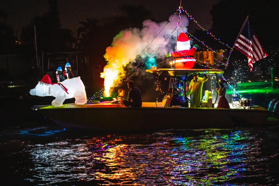 a boat lit up for a holiday parade with a blow-up polar bear in the bow and an American flag at the stern