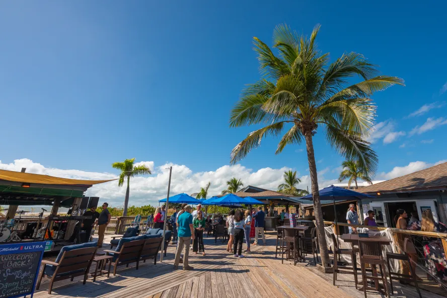 an outdoor bar area next to the beach and palm trees