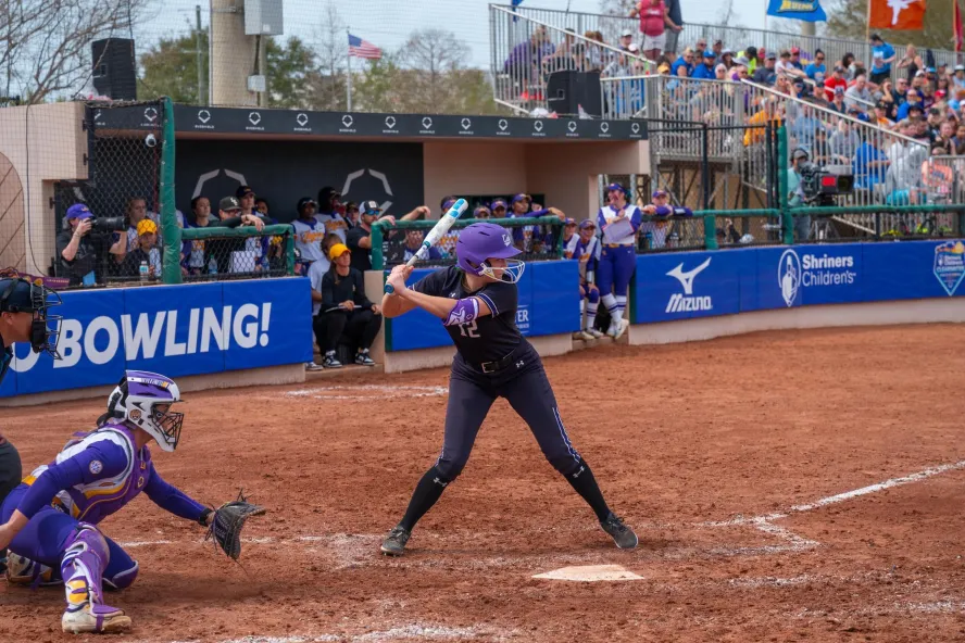 a softball player at bat with the catcher behind her at a tournament
