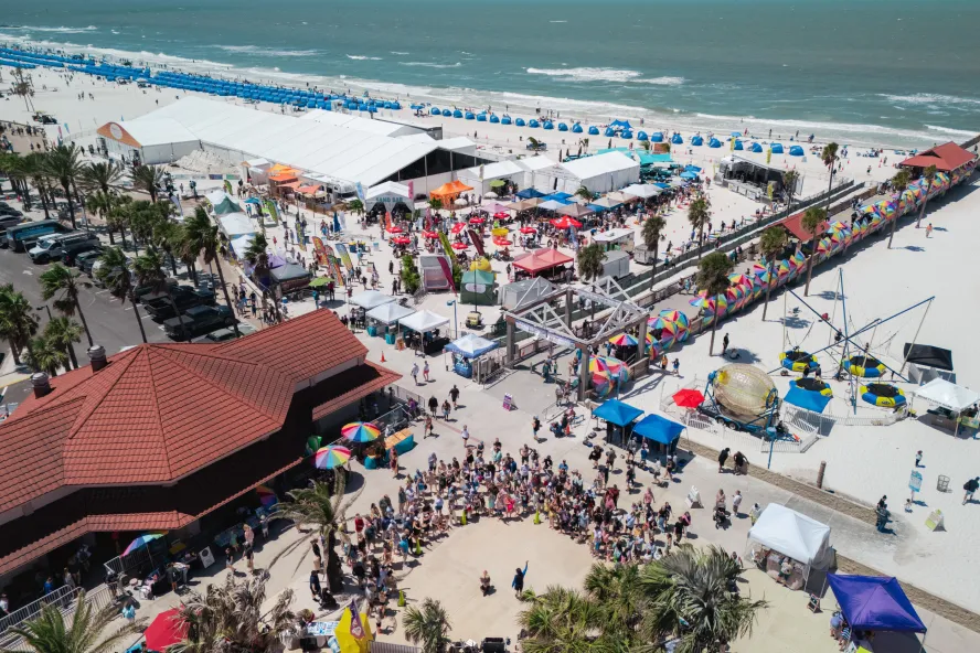 an aerial view of Clearwater Beach with a tent, entertainers and many people at the Pier 60 Sugar Sand Festival