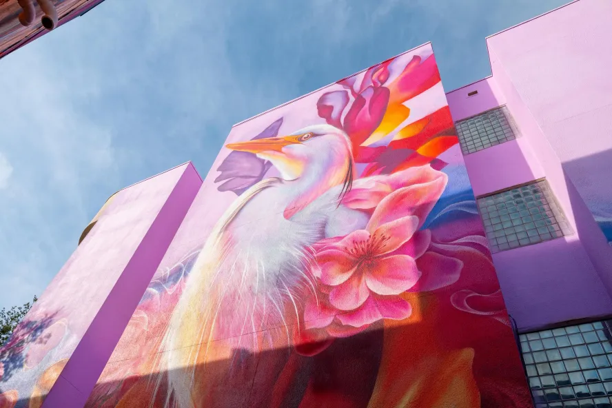 beautiful pink mural of a bird on the side of a building, painted by Dreamweaver