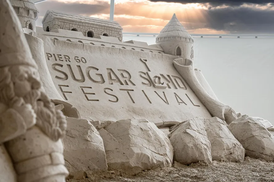 a giant sandcastle with the words Pier 60 Sugar Sand Festival carved in it