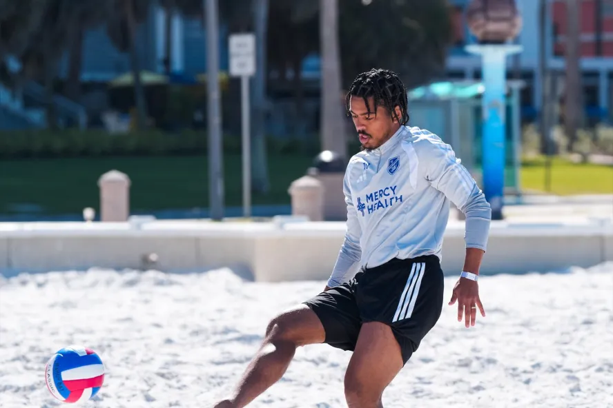 A guy playing volleyball with his foot